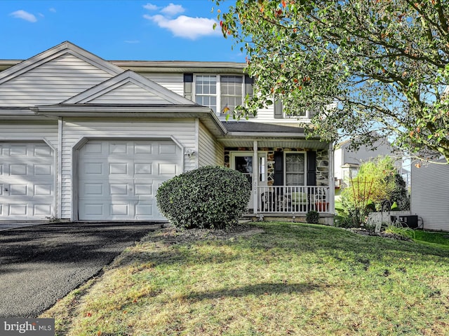 view of front property featuring a front lawn, central AC, covered porch, and a garage