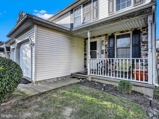 doorway to property with covered porch and a garage