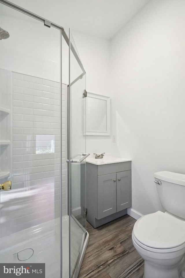 bathroom featuring hardwood / wood-style floors, walk in shower, vanity, and toilet