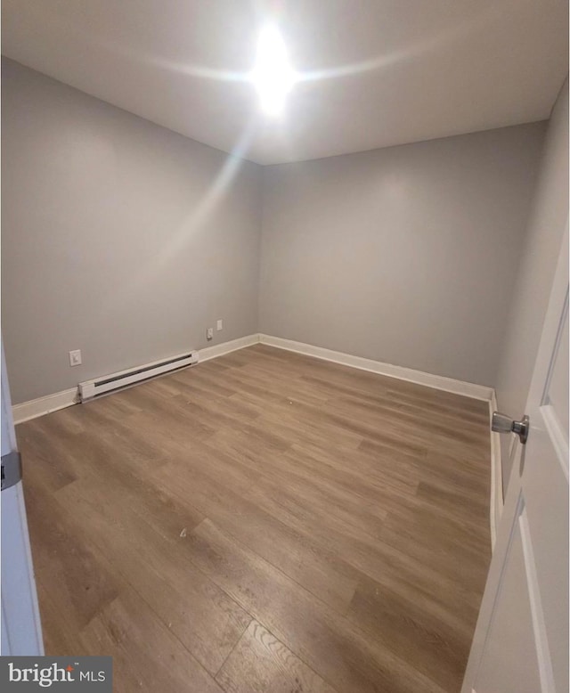 empty room featuring baseboard heating and hardwood / wood-style flooring