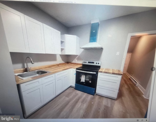 kitchen with butcher block countertops, white cabinetry, wall chimney exhaust hood, and black electric range oven