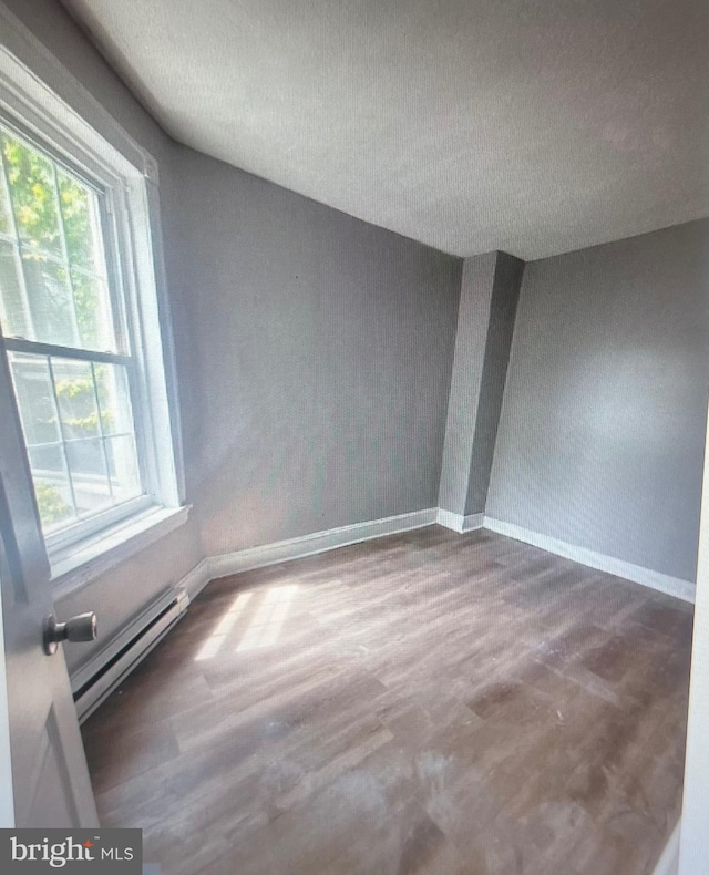 5514 Lansdowne Ave, Philadelphia, PA 19131 - unfurnished room with baseboards, a baseboard radiator, plenty of natural light, a textured ceiling, and wood finished floors