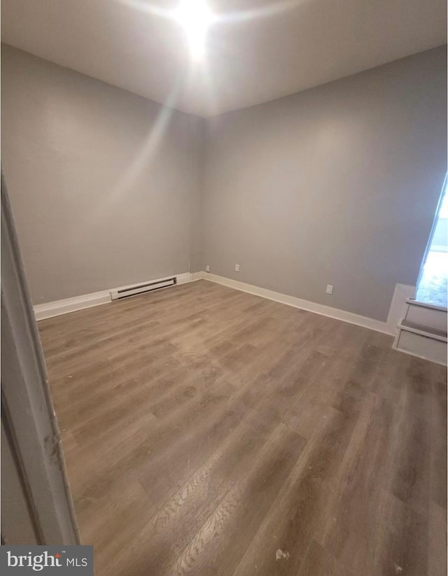 spare room with wood-type flooring and baseboard heating