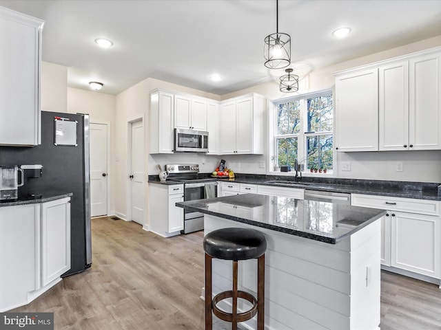 kitchen featuring appliances with stainless steel finishes, light hardwood / wood-style flooring, decorative light fixtures, and white cabinets