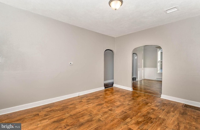 212 W Allen St, Mechanicsburg, PA 17055 - unfurnished room featuring wood finished floors, visible vents, baseboards, baseboard heating, and arched walkways