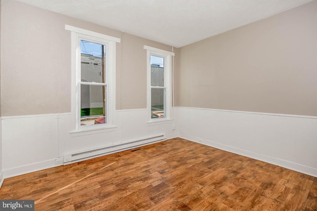 spare room with a baseboard heating unit and hardwood / wood-style flooring