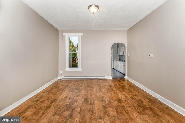 empty room featuring a baseboard radiator, dark wood-type flooring, and a textured ceiling