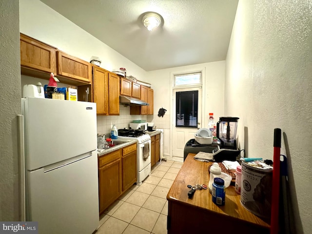 kitchen featuring white appliances, light tile patterned floors, and tasteful backsplash