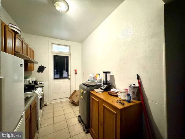 kitchen with lofted ceiling, light tile patterned floors, and white appliances