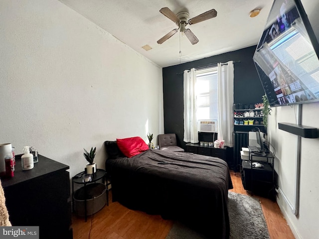 bedroom featuring ceiling fan, hardwood / wood-style floors, and cooling unit