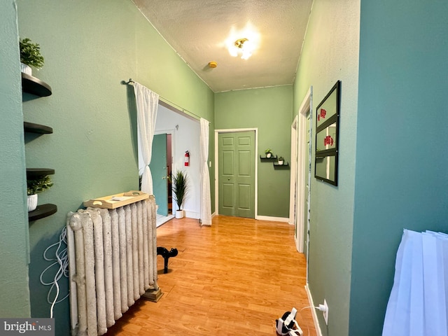 hall featuring a textured ceiling, radiator, and light hardwood / wood-style flooring