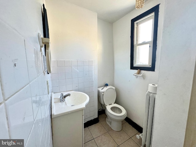 bathroom featuring vanity, radiator, tile patterned flooring, toilet, and tile walls