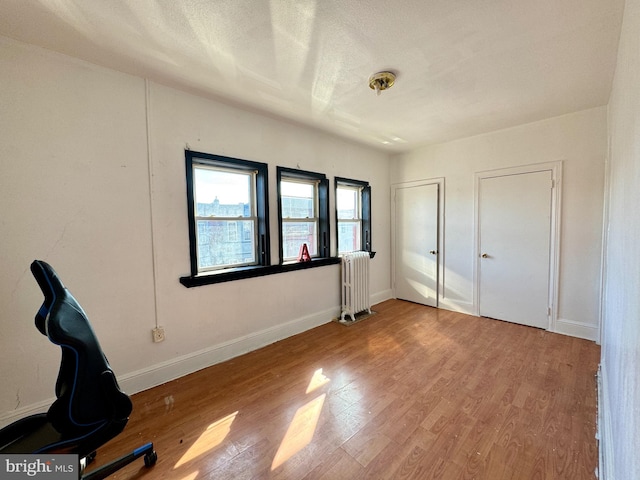 unfurnished bedroom with hardwood / wood-style floors, radiator heating unit, and a textured ceiling