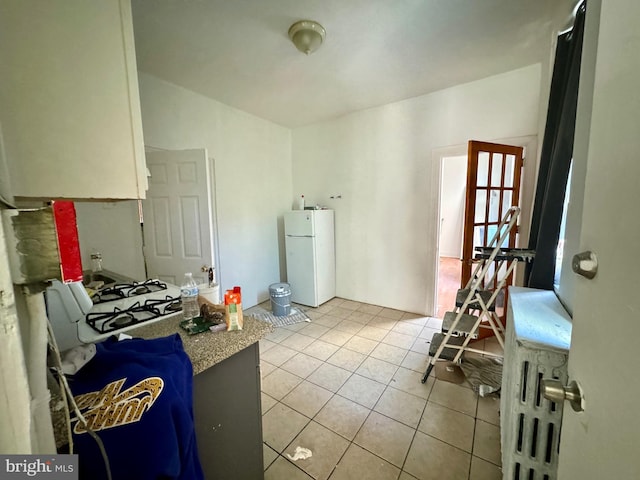 kitchen with white fridge, white cabinetry, and light tile patterned flooring