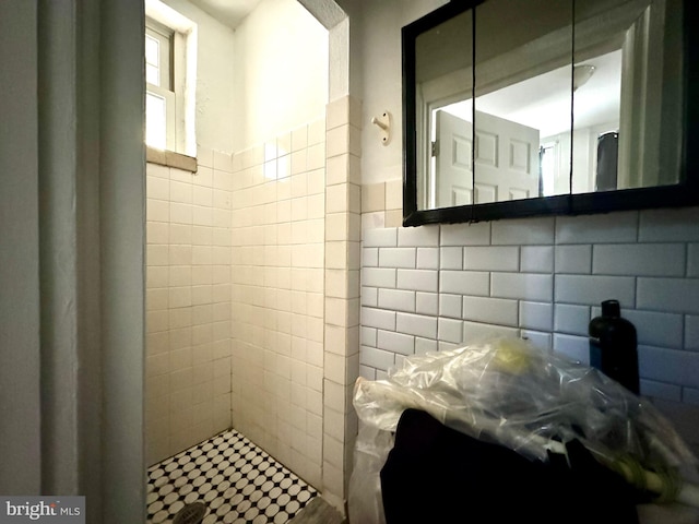 bathroom with decorative backsplash, tile walls, and tiled shower