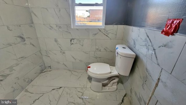 bathroom featuring toilet and tile walls