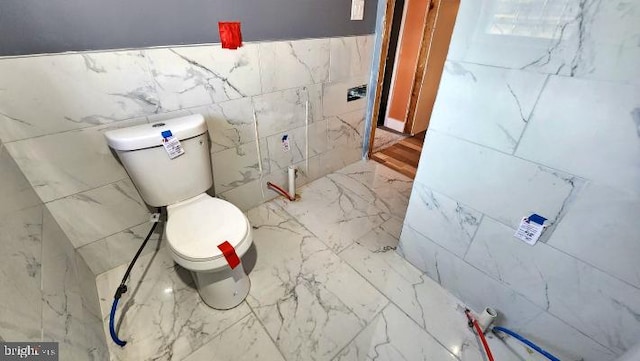 bathroom with toilet and tile walls