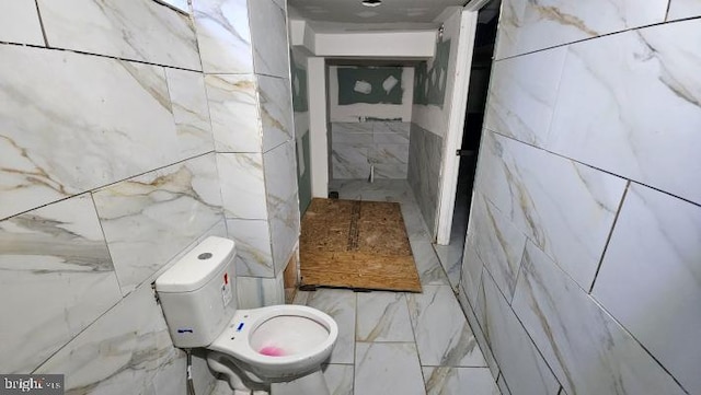 bathroom featuring toilet and tile walls