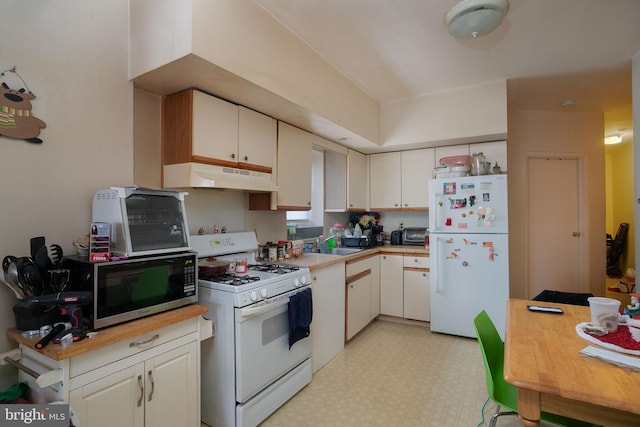 kitchen with light floors, under cabinet range hood, white appliances, a sink, and light countertops