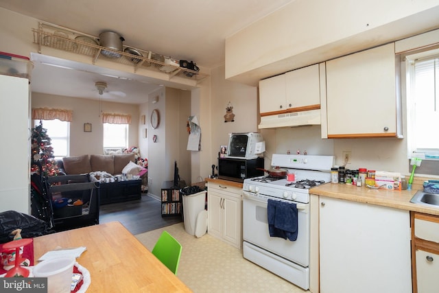 kitchen with white cabinets, decorative light fixtures, and white gas stove