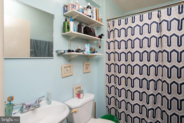 bathroom featuring curtained shower, toilet, and sink