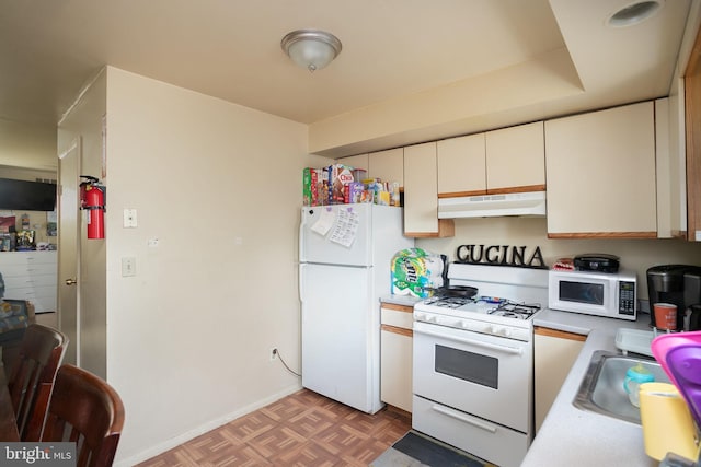 kitchen with sink, white appliances, parquet flooring, and white cabinets