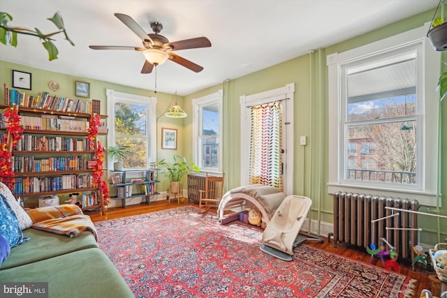 sitting room featuring dark wood-type flooring, radiator, and plenty of natural light