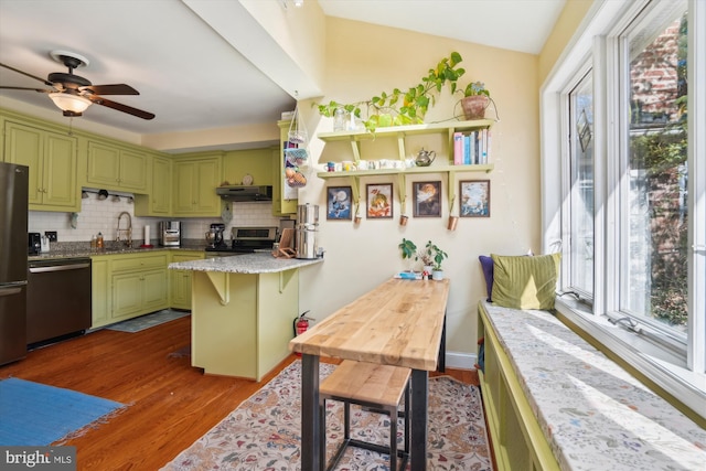 kitchen with stainless steel appliances, sink, green cabinetry, and tasteful backsplash