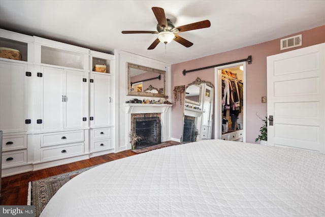 bedroom featuring a walk in closet, ceiling fan, and dark hardwood / wood-style flooring