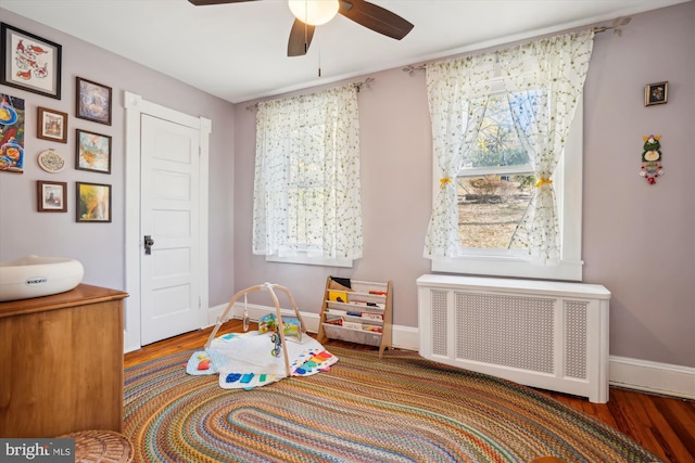 game room with hardwood / wood-style floors, radiator, ceiling fan, and a wealth of natural light