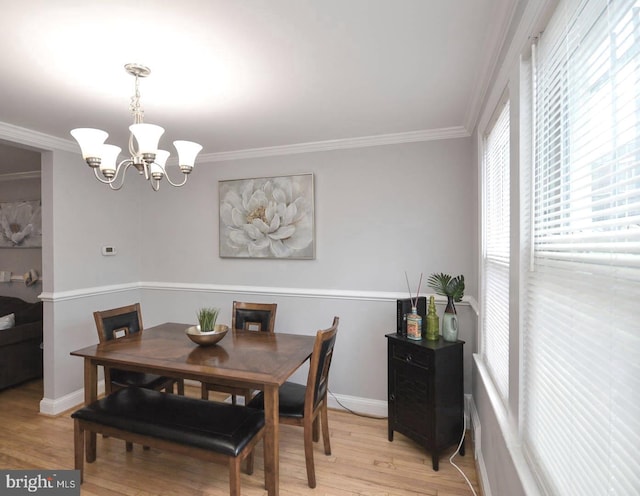 dining area with crown molding, light hardwood / wood-style flooring, and a chandelier