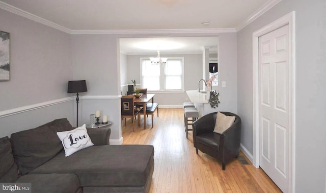 living room featuring light hardwood / wood-style floors, crown molding, sink, and a notable chandelier