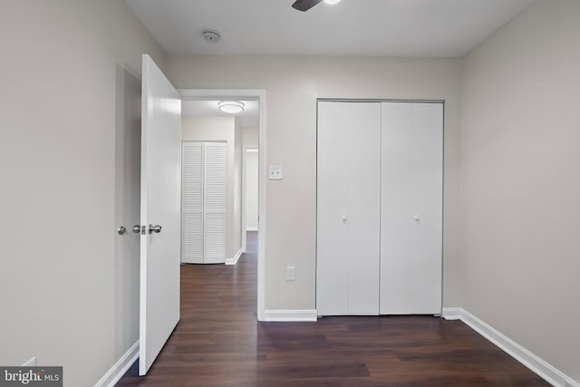 unfurnished bedroom featuring ceiling fan, a closet, and dark wood-type flooring