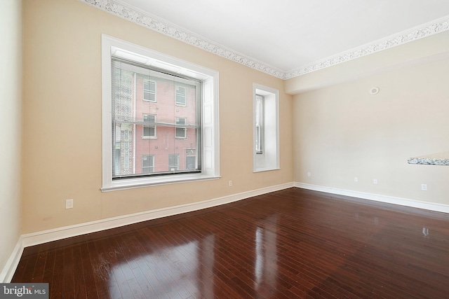 empty room with hardwood / wood-style floors and crown molding