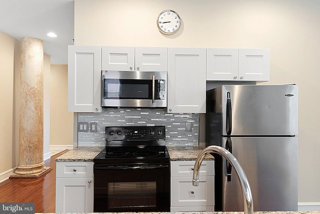 kitchen with white cabinetry, stainless steel appliances, and dark stone counters