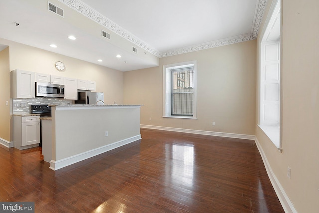 kitchen with dark wood-type flooring, appliances with stainless steel finishes, white cabinetry, and tasteful backsplash