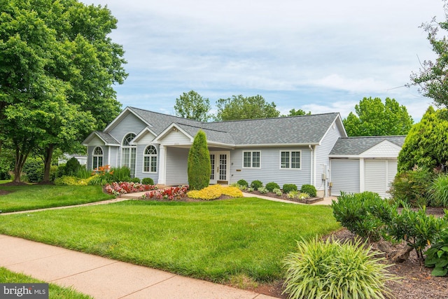 single story home with an attached garage, a shingled roof, and a front yard