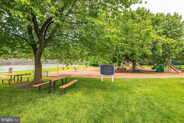 view of community featuring playground community, a yard, and fence