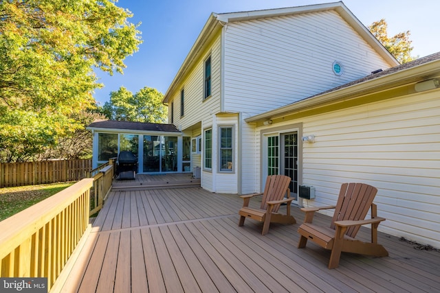 deck with area for grilling, fence, and a sunroom