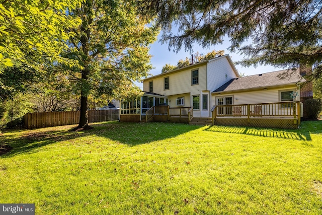 rear view of house with a sunroom, fence, a deck, and a yard