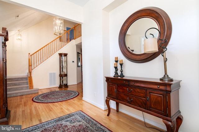 foyer entrance with light hardwood / wood-style floors and a notable chandelier