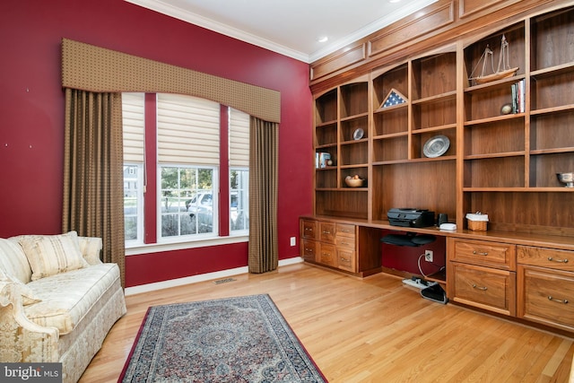 office space with built in desk, light hardwood / wood-style flooring, and crown molding