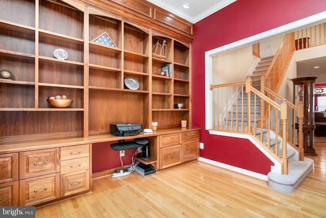 office space with light wood-type flooring, built in desk, and crown molding