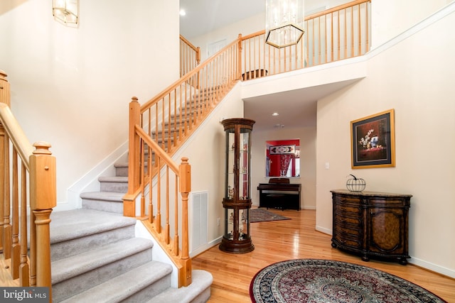 stairway with hardwood / wood-style flooring and a high ceiling