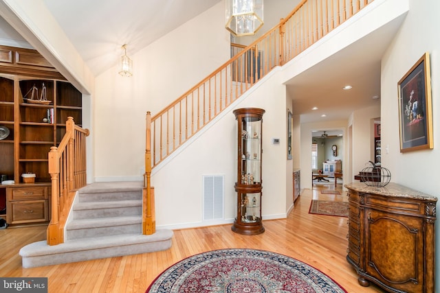 stairway with ceiling fan with notable chandelier and wood-type flooring