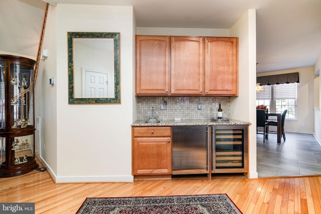 bar with wine cooler, decorative backsplash, stainless steel fridge, and light hardwood / wood-style flooring