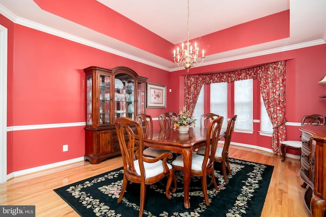 dining space featuring a tray ceiling, an inviting chandelier, and hardwood / wood-style flooring