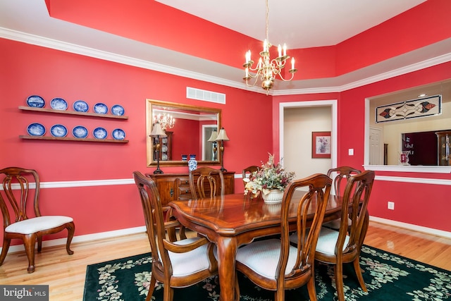 dining room featuring wood-type flooring, crown molding, and a notable chandelier