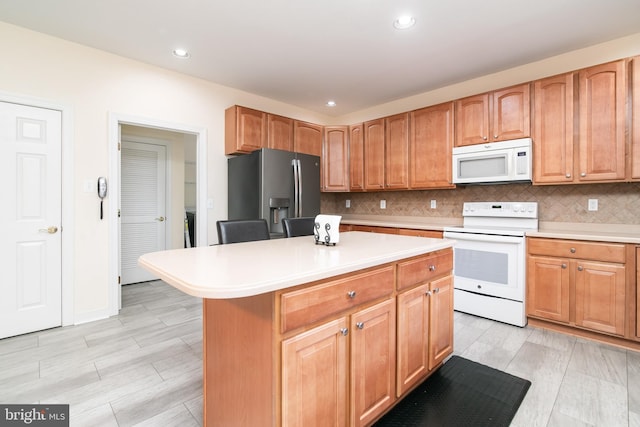 kitchen with a center island, white appliances, and backsplash