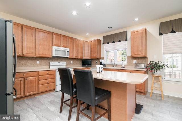 kitchen with a kitchen bar, tasteful backsplash, white appliances, and a kitchen island